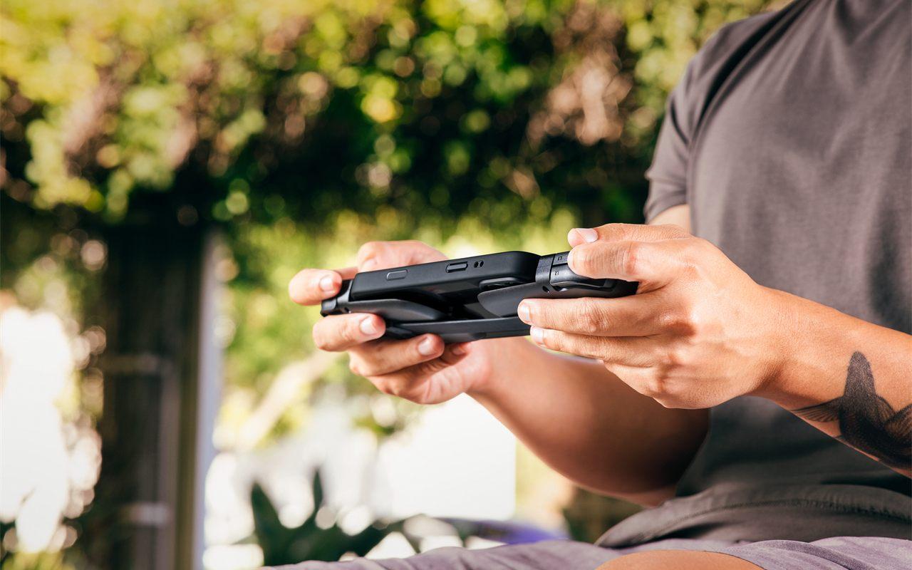 Deux mains jouent en extérieur avec la Razer Prio déployée autour d'un smartphone