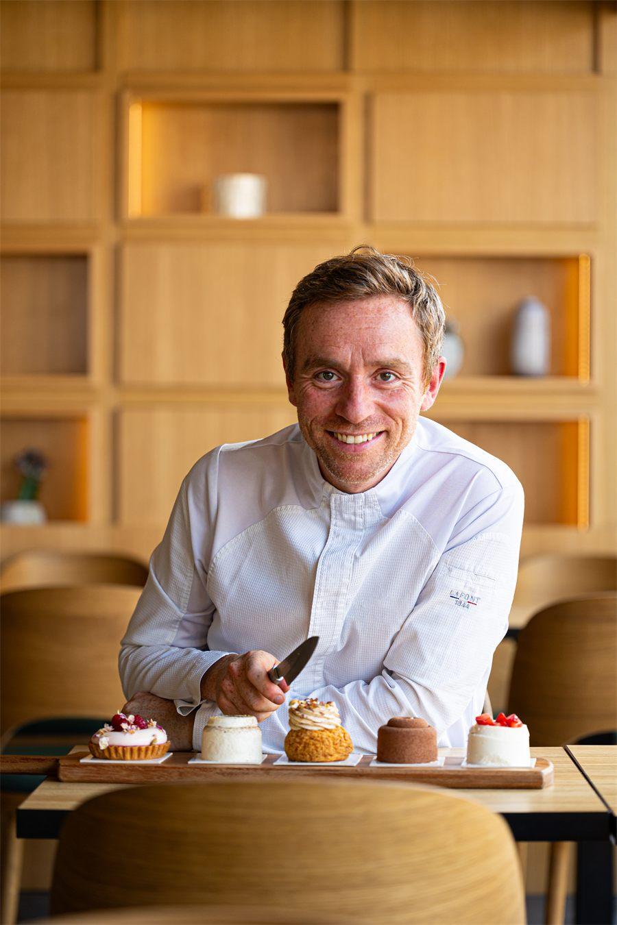 Le chef pâtissier Nicolas Paciello attablé devant un plateau de ses créations
