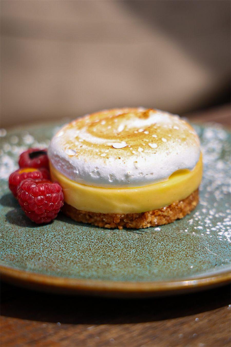 Gros plan sur la meringue passée au chalumeau du sablé aux deux citrons, avec trois framboises