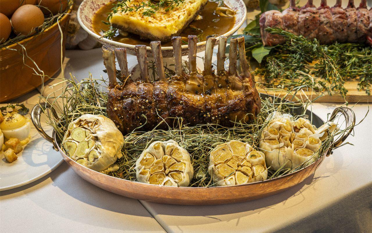 Carré de côtelettes rôti et têtes d'ail sur plat en cuivre