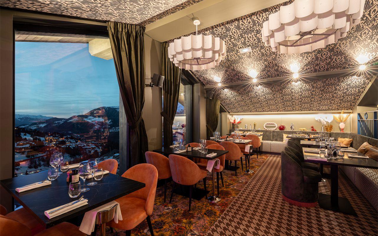 Salle de La Bokka à Courchevel, fauteuils orange et vue sur la vallée enneigée