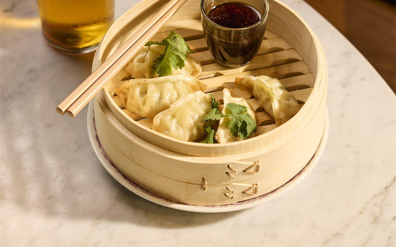 Gyozas vapeur et sauce pimentée dans leur panier en bambou, sur une table en marbre