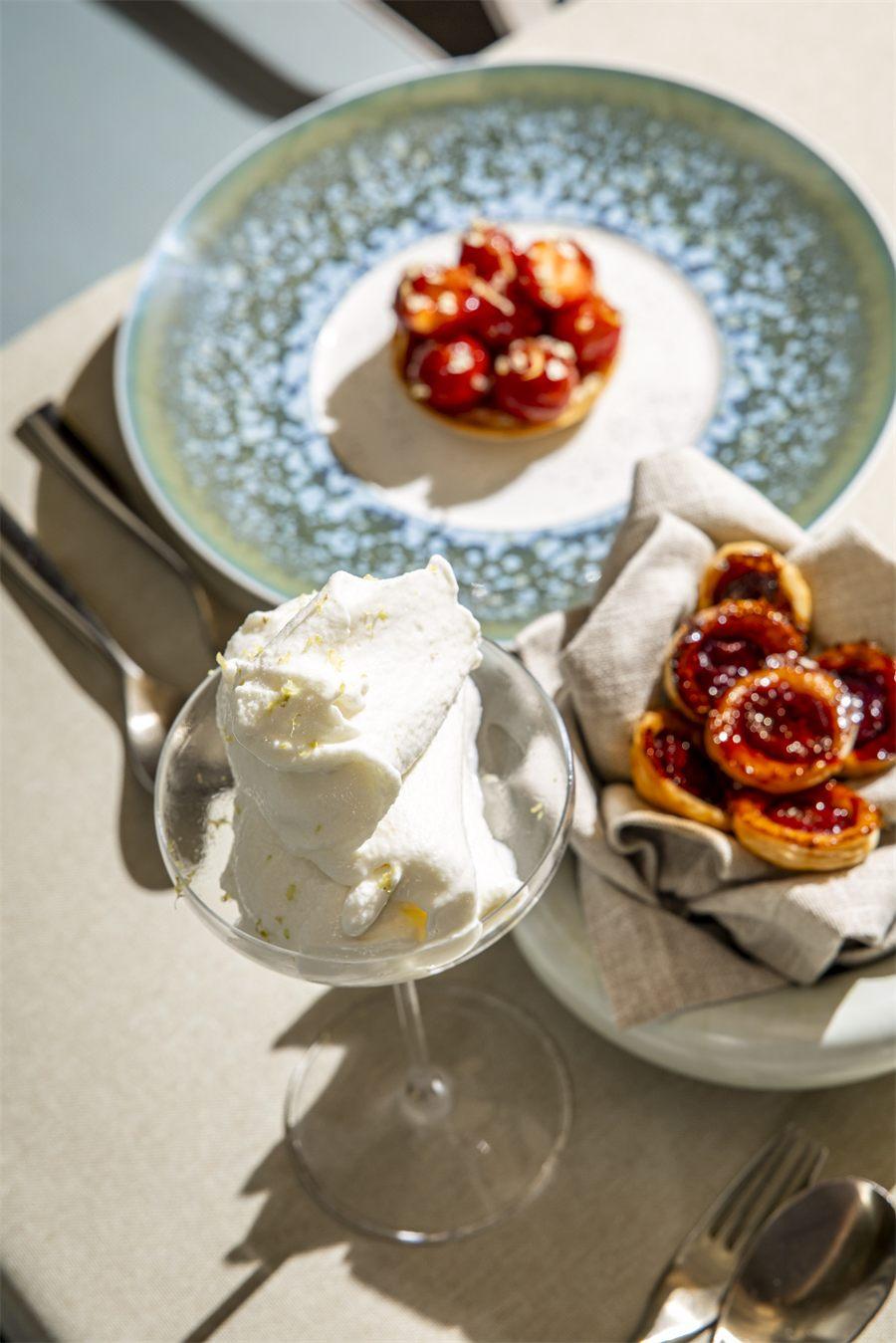 Tartelette aux fruits rouges sur assiette bleue, coupe de sorbet aux zestes de citron et panier de petites tartes rouges