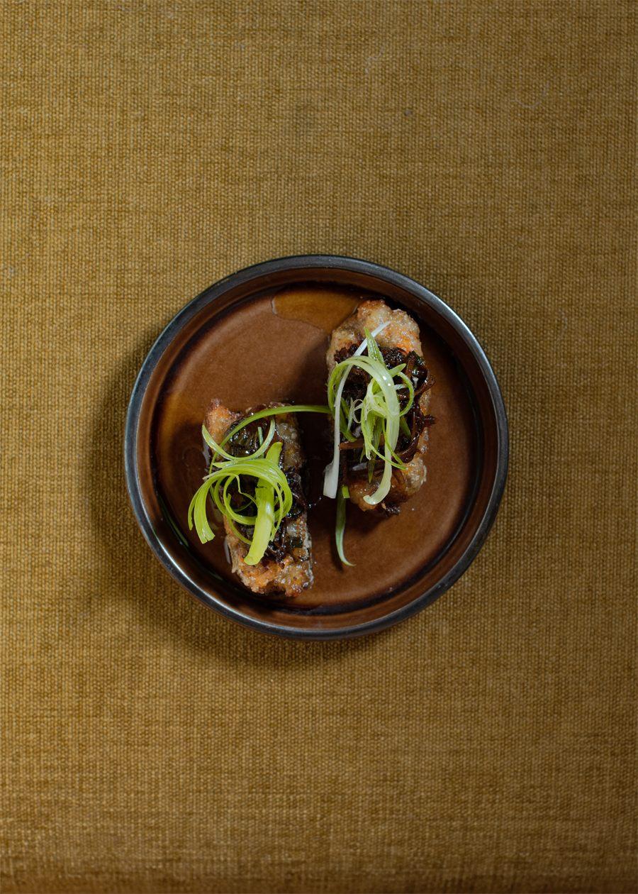 Deux bouchees frites surmontees de cebette, servies dans une assiette en gres chez SOBO