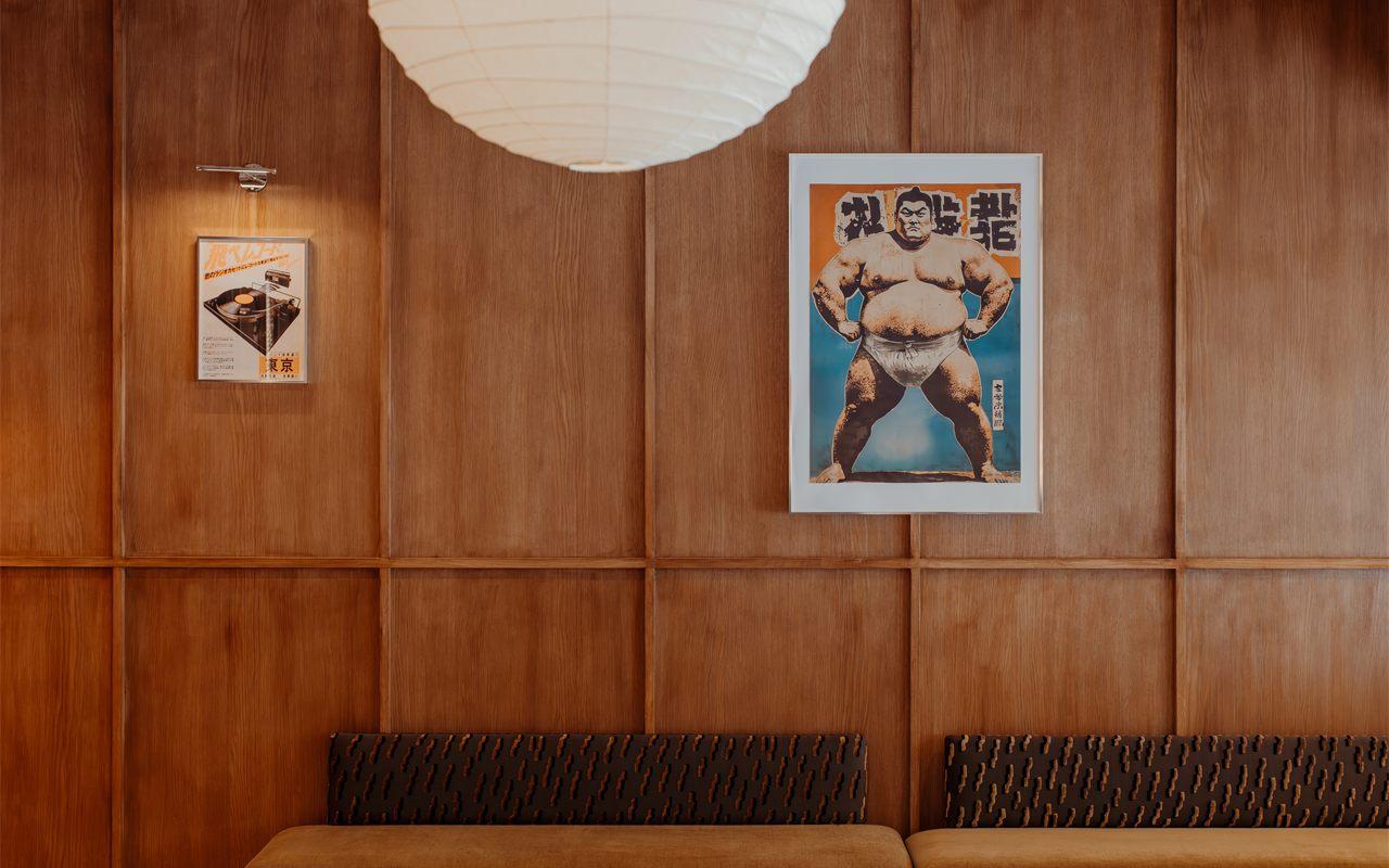 Plafonnier en papier d'Isamu Noguchi, affiche de sumo et banquettes devant les panneautages de chene