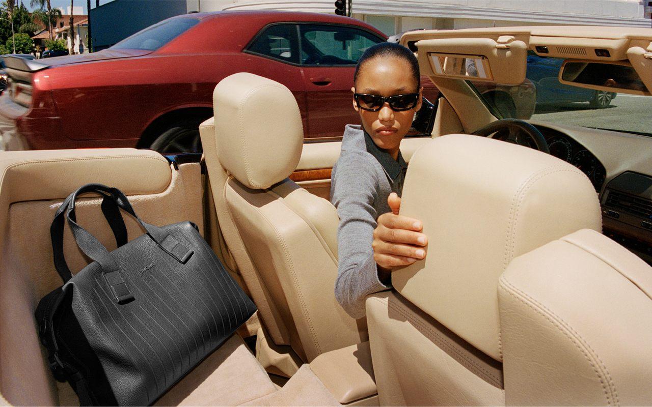 Cabas Zippe RIMOWA en cuir noir pose sur la banquette d un cabriolet a Los Angeles
