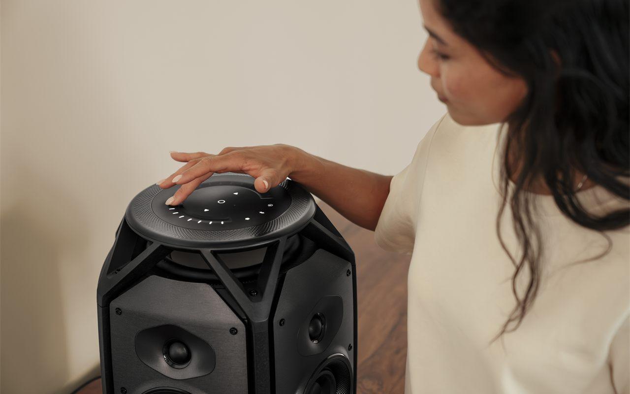 Main posée sur la surface tactile du Teufel IKONIO, commandes rétroéclairées sur le dessus