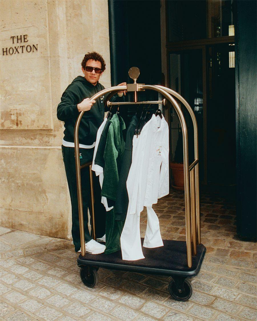 Chariot a bagages charge des pieces The Hoxton x Lacoste devant la facade de l'hotel