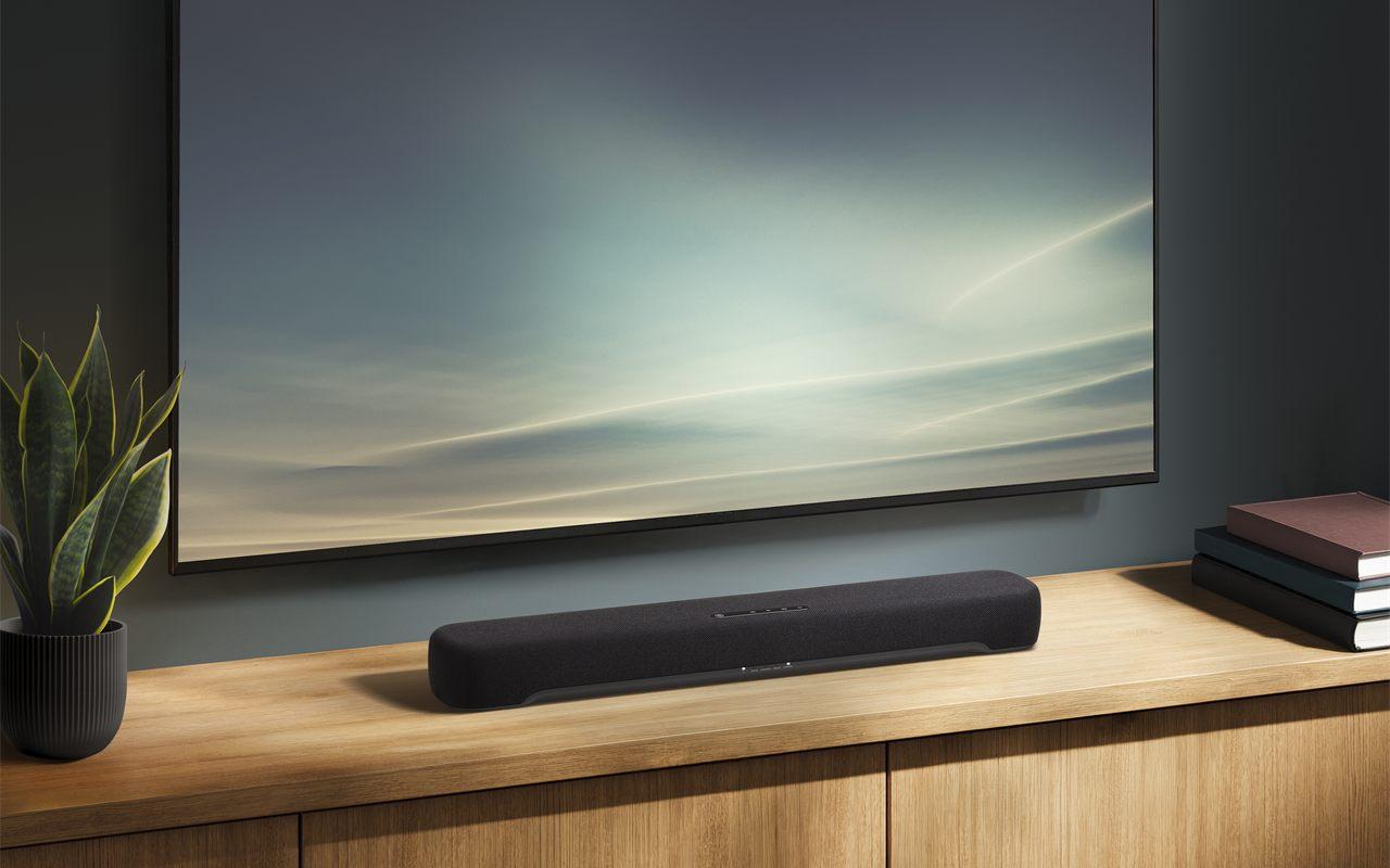 La barre de son Yamaha B200A posée sur un meuble en bois devant un téléviseur mural