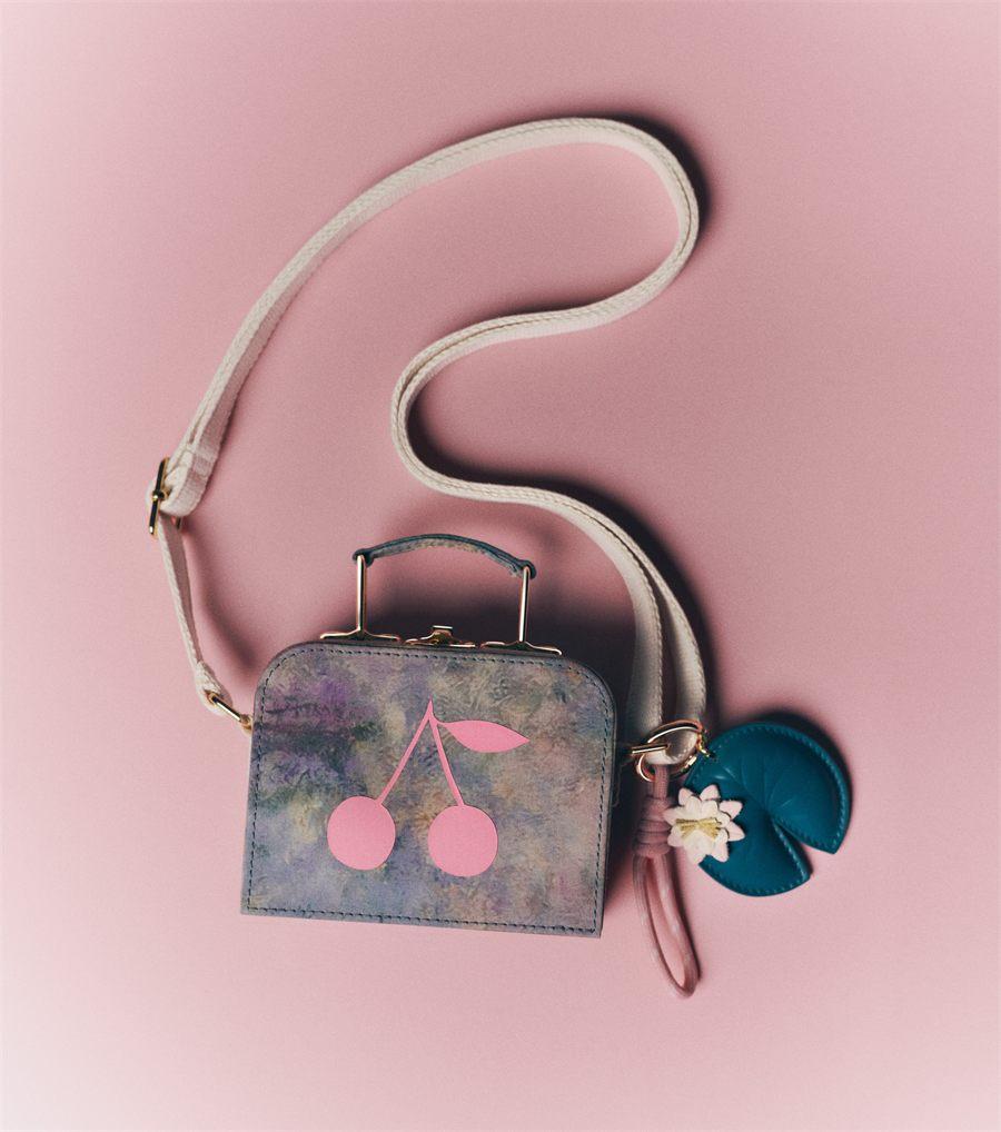 Valisette Aimane Bonpoint x MoMA ornée de deux cerises roses, avec le porte-clés nénuphar
