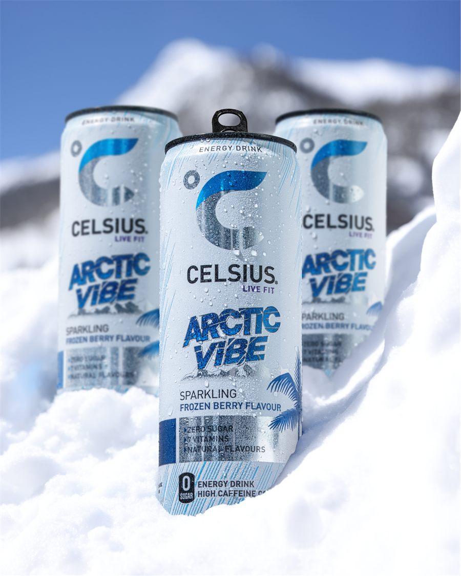 Trois canettes Celsius Arctic Vibe dans la neige, devant un sommet sous le ciel bleu
