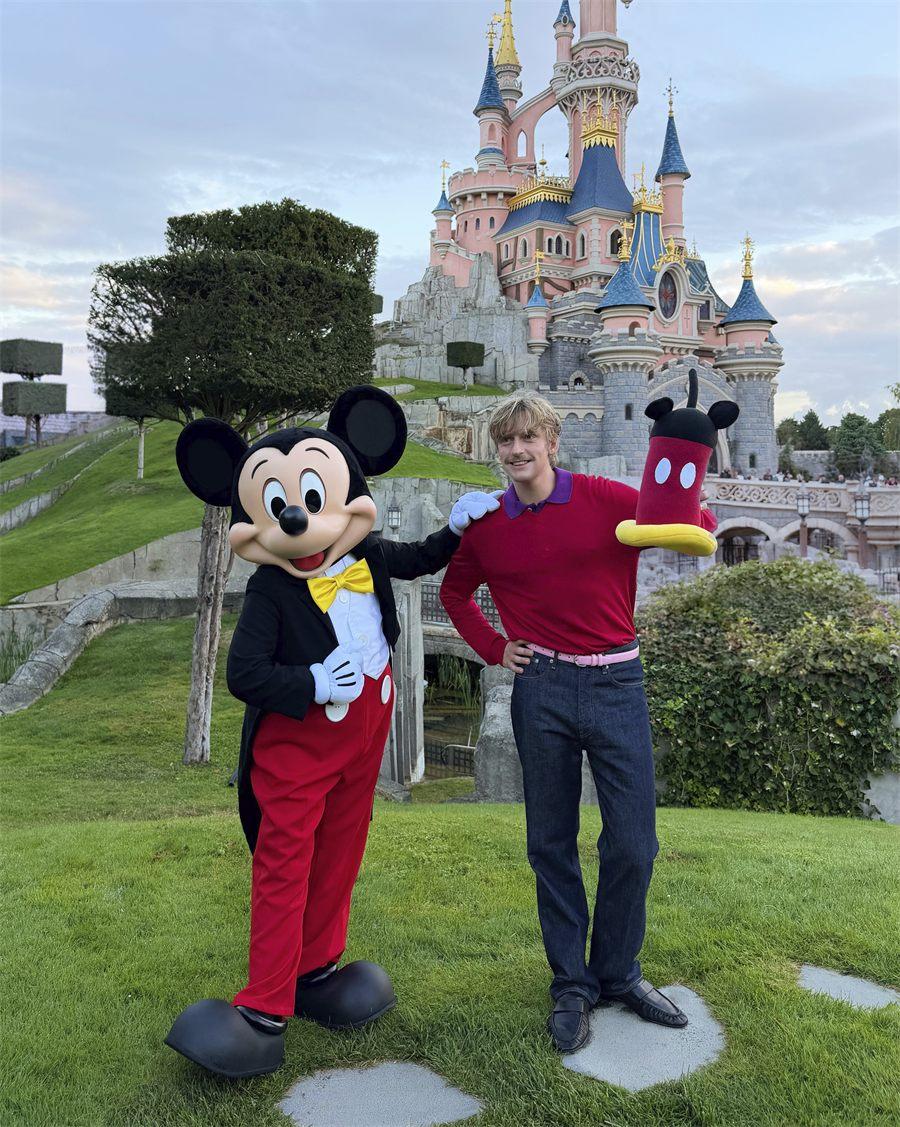 Gustaf Westman pose avec Mickey devant le château de la Belle au bois dormant