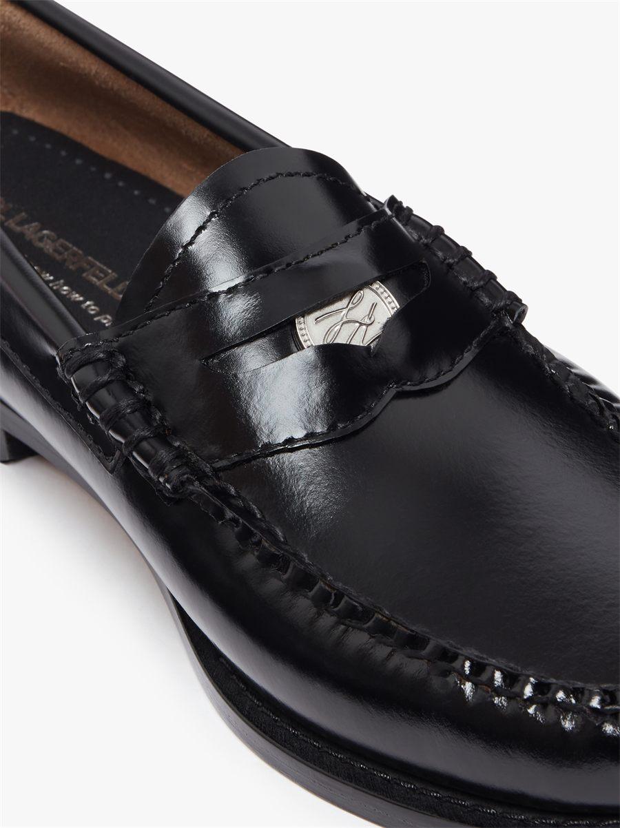 Médaillon argenté signé Karl Lagerfeld dans la bride d'un mocassin penny noir