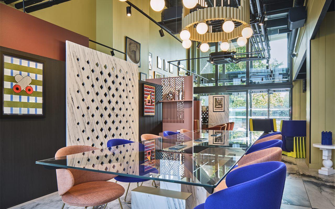 Hall de l'hôtel, chaises bleu Klein et vieux rose autour d'une table de verre