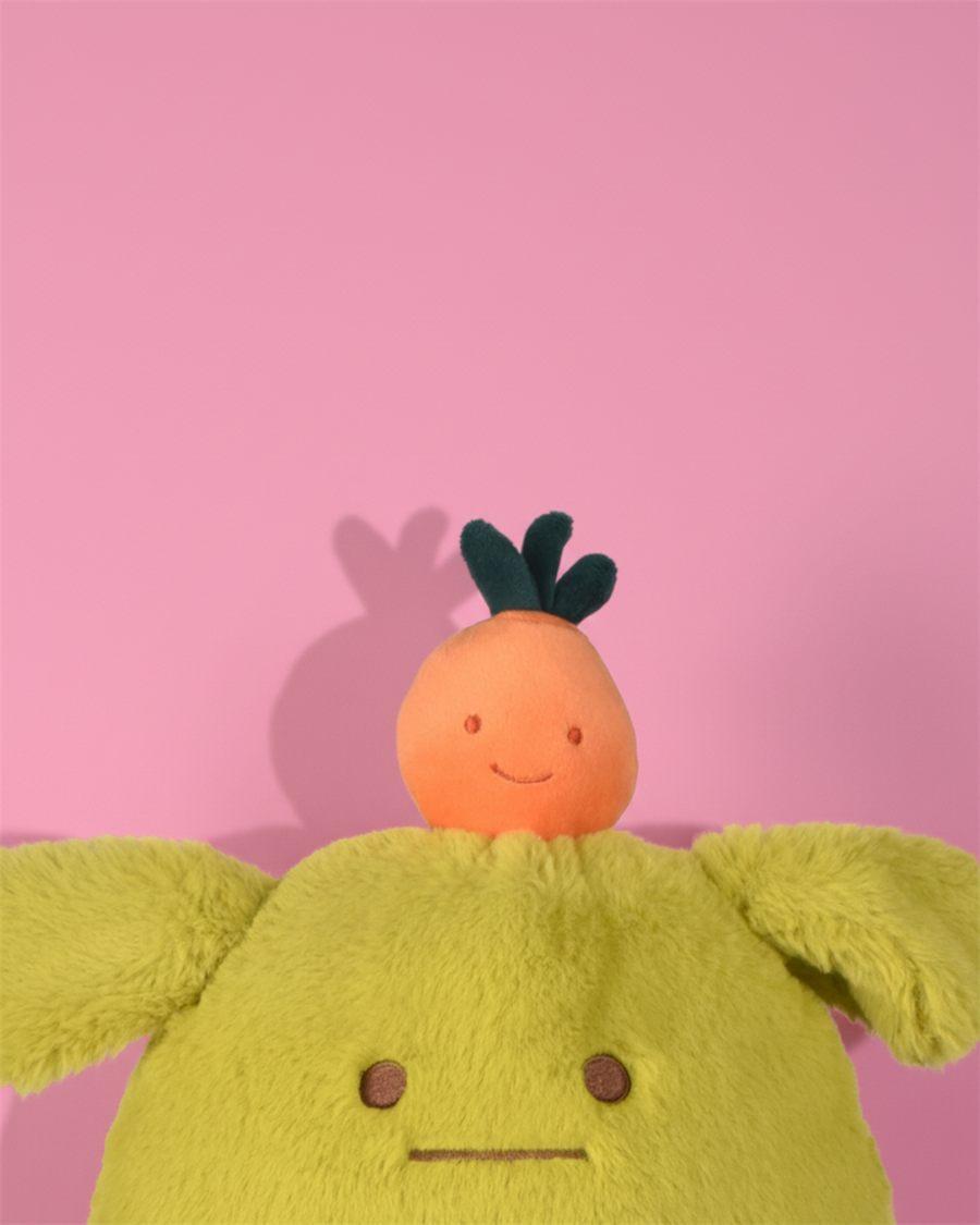 Gros plan sur la peluche MIAM Laurent Jade, verte, coiffée d'un petit fruit orange