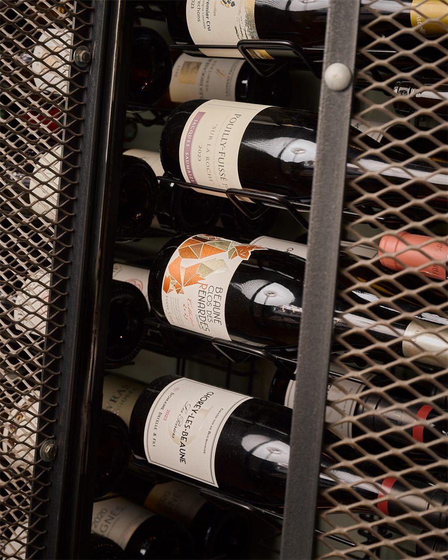 Bouteilles de vin rangées dans la cave grillagée du restaurant Aldéhyde