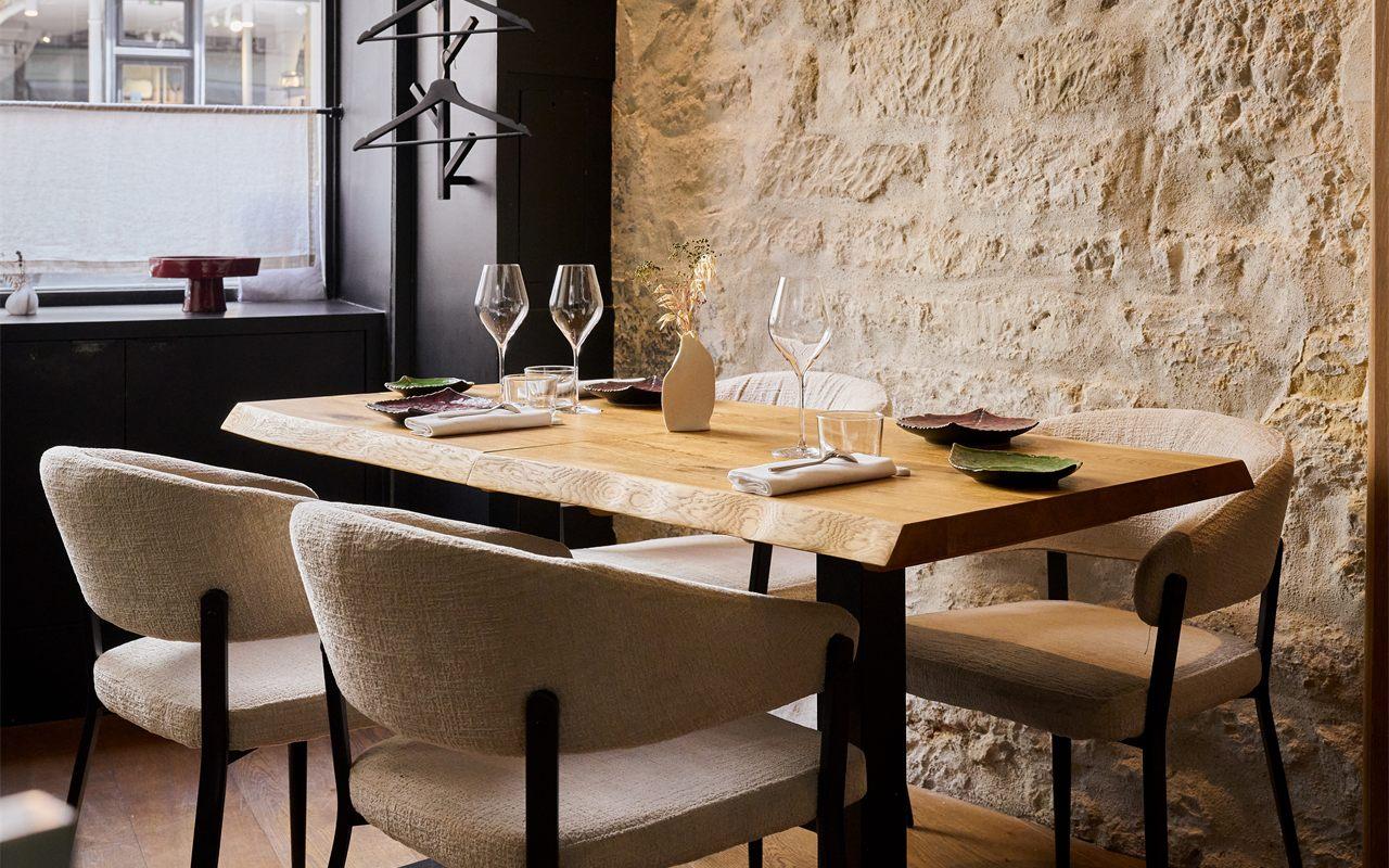 La salle du restaurant Aldéhyde, ses tables en bois et son mur de pierre apparente