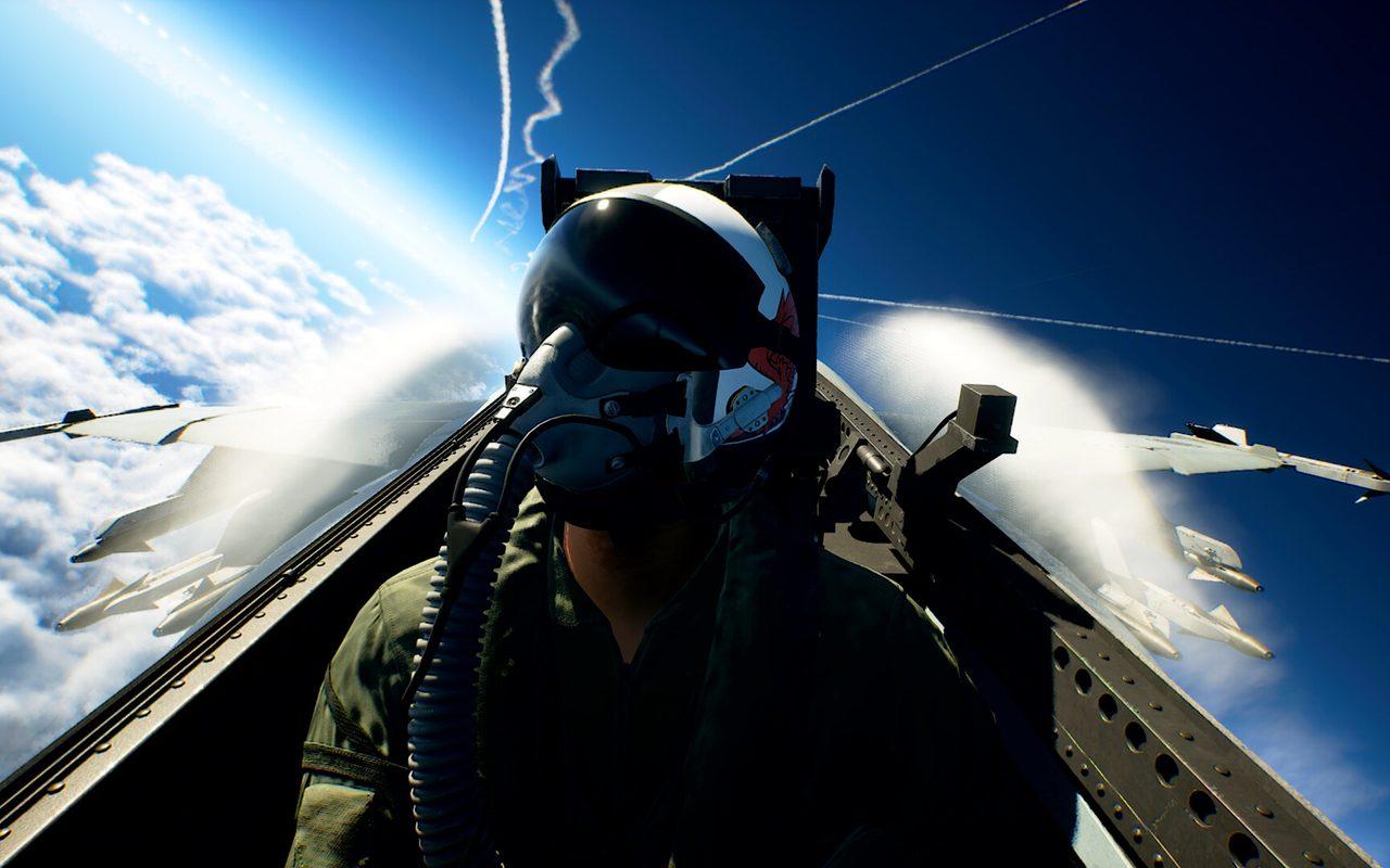Un pilote casqué dans son cockpit, au-dessus des nuages, sous un ciel bleu