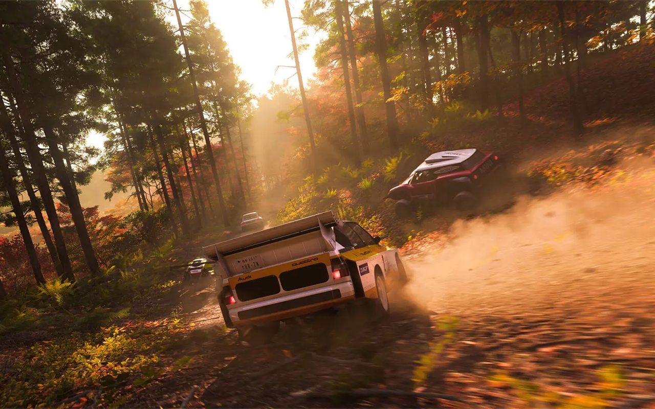 Voitures de rallye soulevant la terre d'une piste forestière en automne