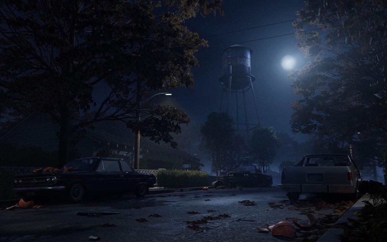 Une rue de Haddonfield sous la lune, voitures garées et château d'eau au loin