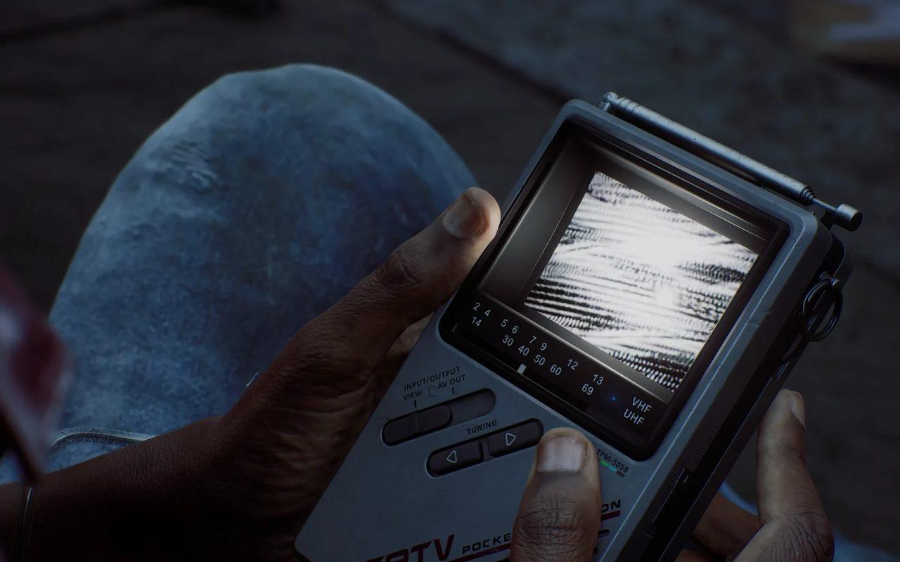 Deux mains tiennent la CRTV, une télévision portable à tube cathodique qui grésille