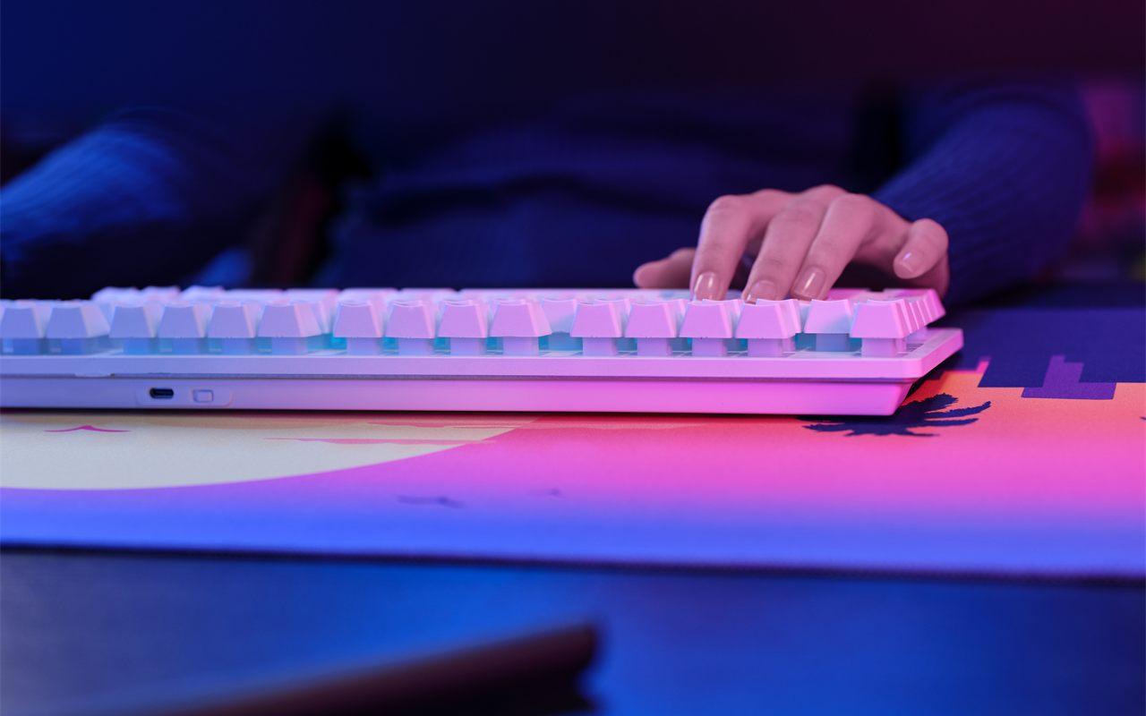 Clavier TKL sans fil blanc et rétroéclairé du pack Trust posé sur le tapis XXL
