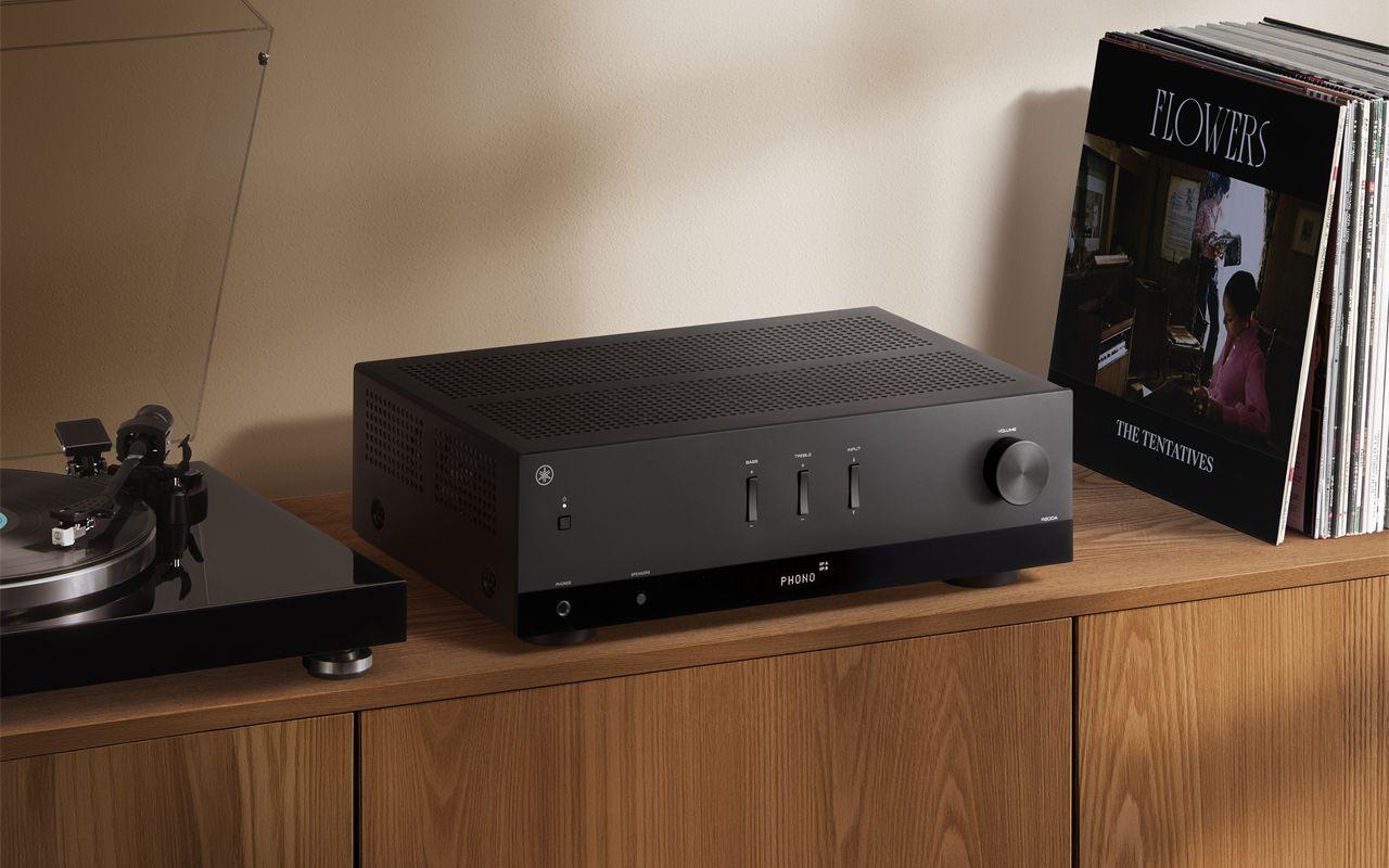 L'ampli-tuner Yamaha R200A noir posé entre une platine vinyle et une pile de disques