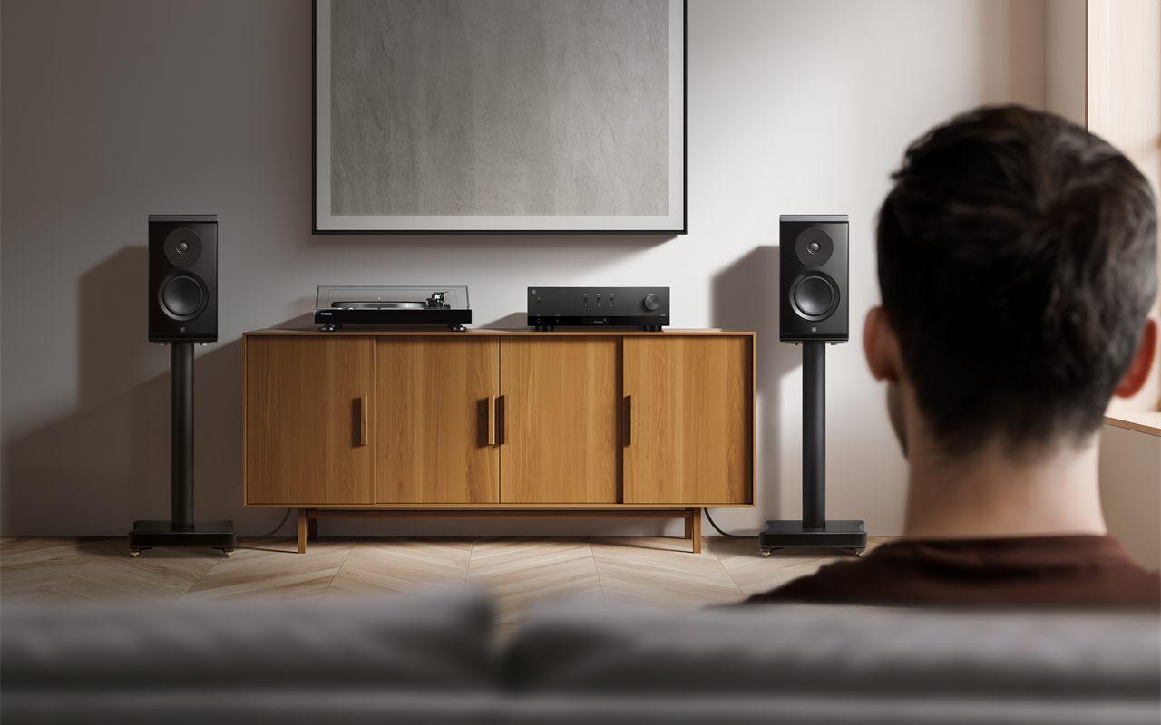 Un auditeur face à une chaîne Hi-Fi composée du Yamaha R200A, d'une platine et d'enceintes